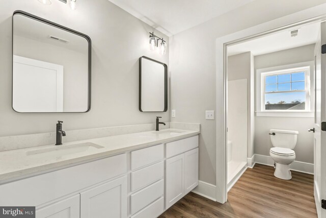 bathroom with double vanity, toilet, and hardwood / wood-style floors