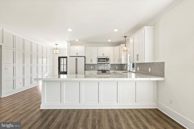 kitchen with dark wood-type flooring, appliances with stainless steel finishes, white cabinets, kitchen peninsula, and sink