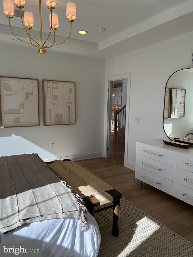 bedroom with a chandelier, a tray ceiling, and dark hardwood / wood-style flooring