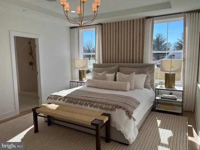 bedroom with a chandelier, a tray ceiling, multiple windows, and hardwood / wood-style flooring