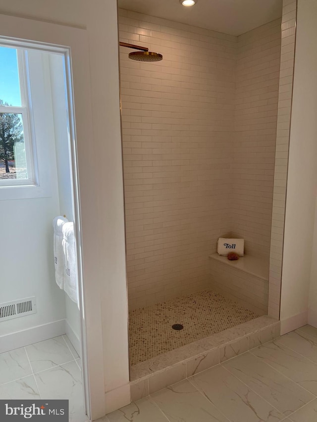 bathroom with a tile shower and tile floors