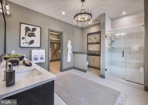 bathroom featuring a notable chandelier, walk in shower, tile floors, and vanity