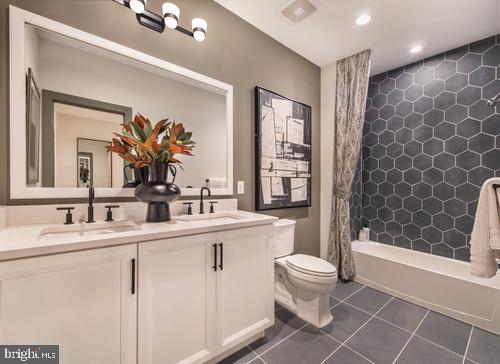 full bathroom featuring toilet, shower / tub combo, tile floors, and dual bowl vanity