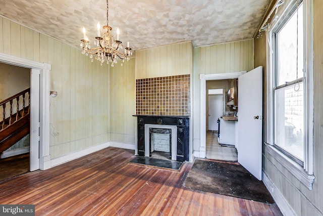 unfurnished living room with dark hardwood / wood-style flooring, plenty of natural light, and a chandelier