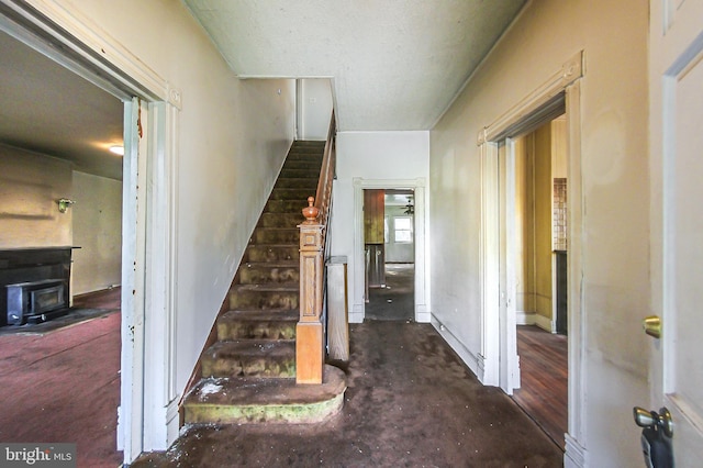 staircase featuring dark wood-type flooring and a wood stove