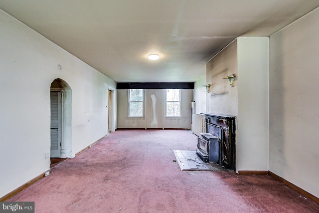 unfurnished living room with carpet floors and a wood stove