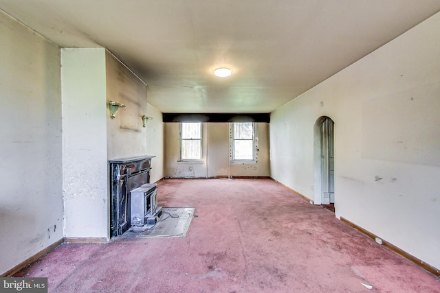 unfurnished living room featuring carpet floors and a wood stove