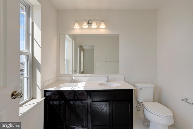 bathroom with dual vanity, tile floors, a healthy amount of sunlight, and toilet