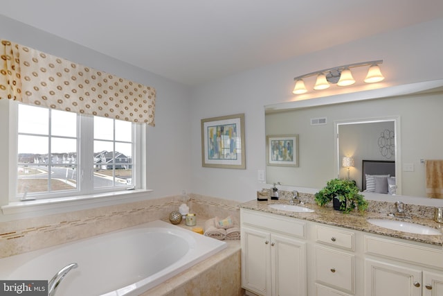 bathroom featuring tiled bath and double vanity