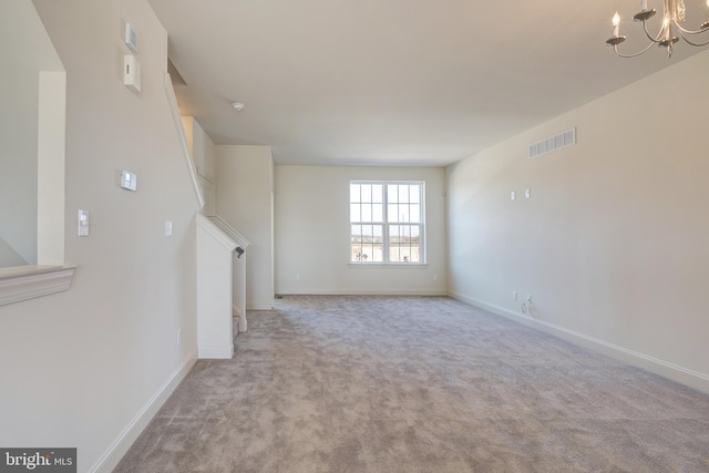 empty room with an inviting chandelier and light colored carpet