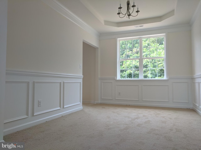 spare room featuring a notable chandelier, a raised ceiling, ornamental molding, and light colored carpet