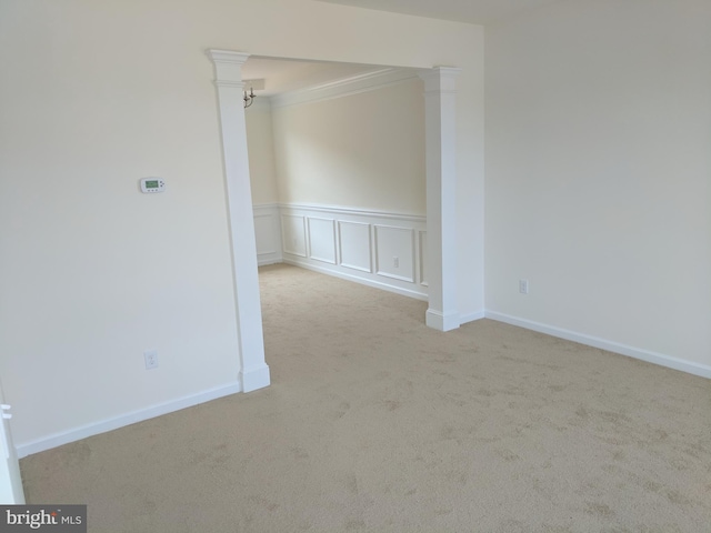 unfurnished room with light carpet, ornate columns, and ornamental molding