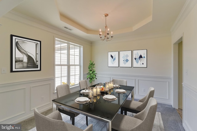 carpeted dining room featuring a raised ceiling, an inviting chandelier, and ornamental molding