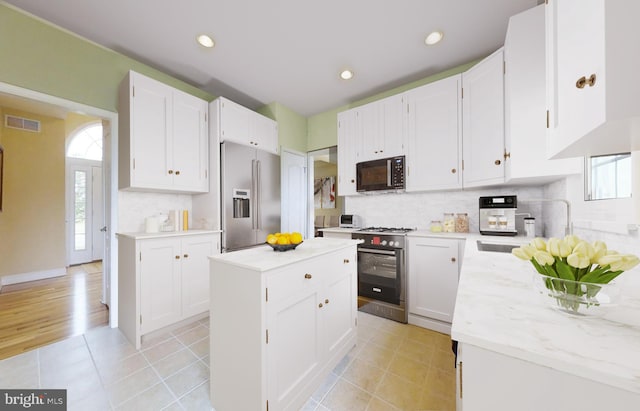 kitchen with tasteful backsplash, white cabinetry, appliances with stainless steel finishes, and light wood-type flooring