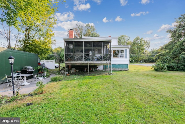 rear view of property featuring a yard, a sunroom, and a patio area