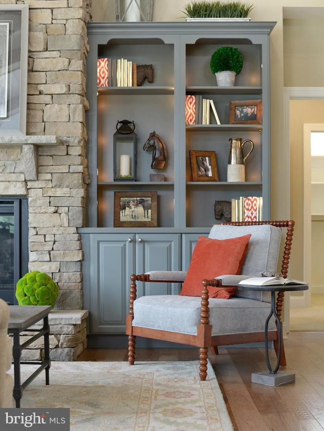 sitting room with a fireplace, dark hardwood / wood-style floors, and built in shelves