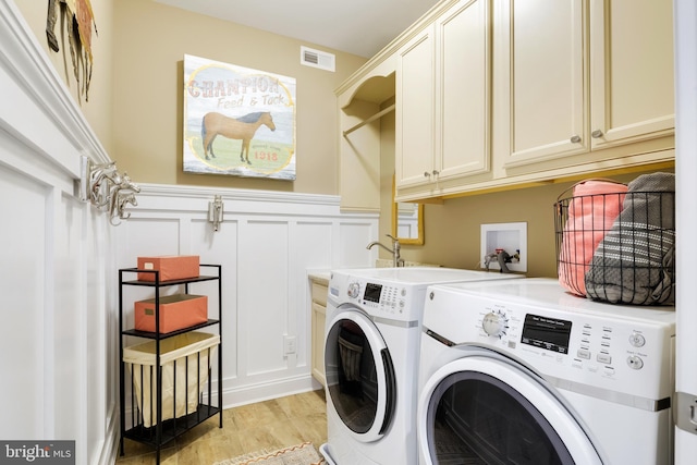 clothes washing area featuring washing machine and clothes dryer, cabinets, washer hookup, and light hardwood / wood-style floors