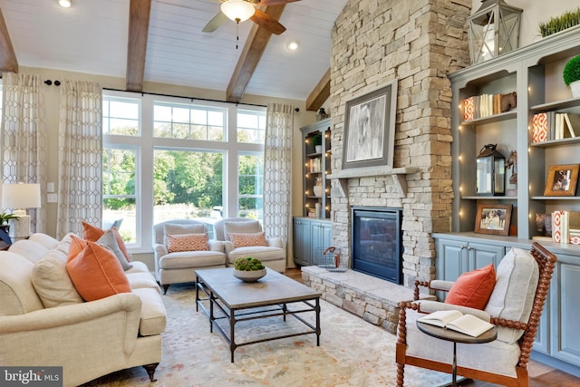 living room featuring high vaulted ceiling, a fireplace, beam ceiling, ceiling fan, and light hardwood / wood-style flooring