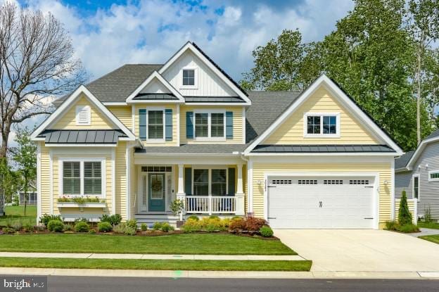 craftsman inspired home with covered porch, a front yard, and a garage