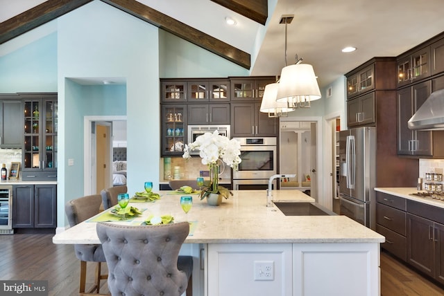 kitchen featuring appliances with stainless steel finishes, tasteful backsplash, beam ceiling, decorative light fixtures, and a kitchen breakfast bar