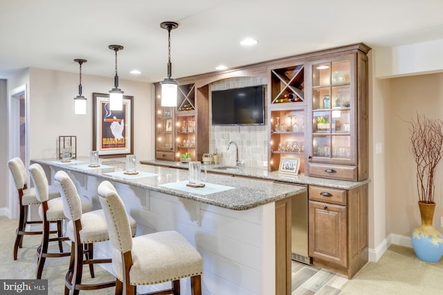 bar featuring sink, light colored carpet, light stone countertops, and pendant lighting