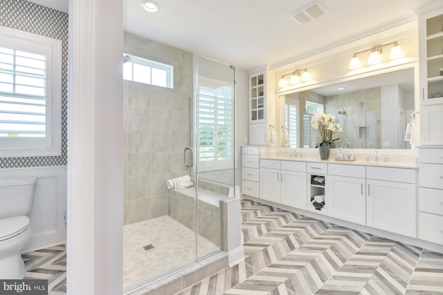 bathroom featuring tile flooring, toilet, a shower with shower door, vanity with extensive cabinet space, and double sink