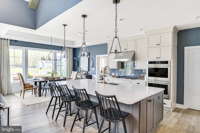 kitchen featuring light hardwood / wood-style floors, a breakfast bar area, a center island with sink, stainless steel appliances, and sink