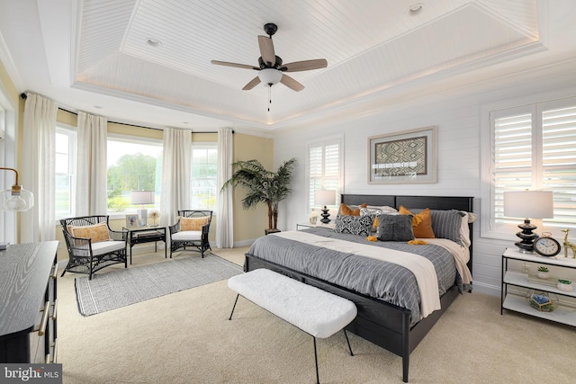 bedroom with ceiling fan, ornamental molding, light colored carpet, and a raised ceiling