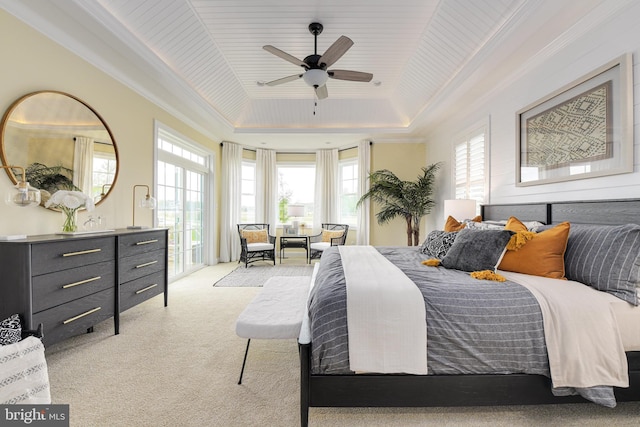 carpeted bedroom with ceiling fan, ornamental molding, and a tray ceiling