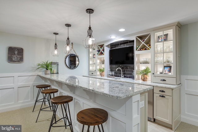 bar featuring decorative light fixtures, light colored carpet, sink, and light stone counters