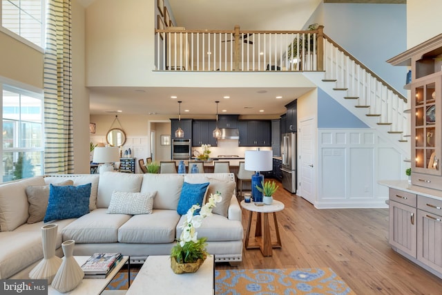 living room with a towering ceiling and light wood-type flooring