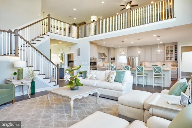 living room with light hardwood / wood-style flooring, ceiling fan, and a towering ceiling