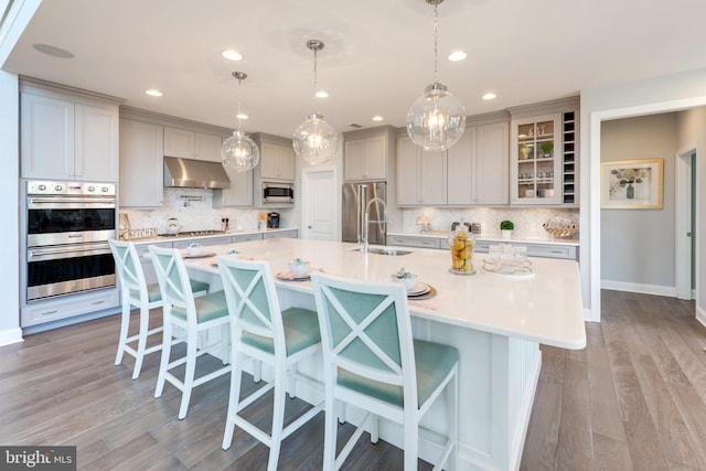 kitchen with a breakfast bar, stainless steel appliances, and a center island with sink