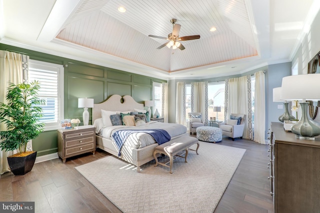 bedroom featuring ornamental molding, dark hardwood / wood-style flooring, ceiling fan, and a tray ceiling