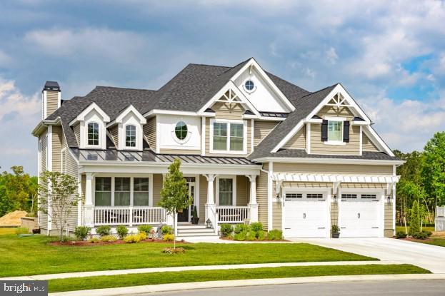 craftsman inspired home with covered porch, a front yard, and a garage