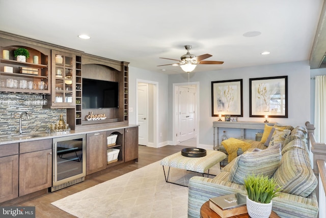 living room featuring beverage cooler, ceiling fan, hardwood / wood-style flooring, and sink