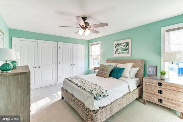 carpeted bedroom featuring multiple closets and ceiling fan