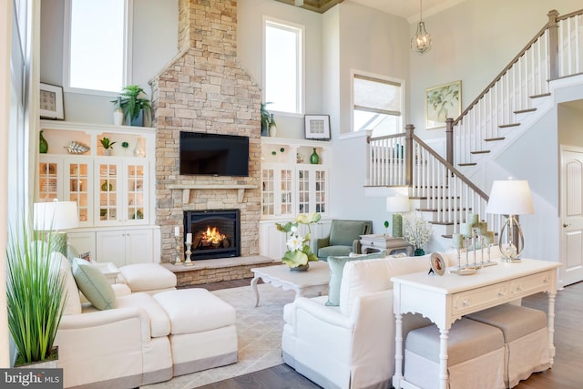 living room featuring a high ceiling, light hardwood / wood-style floors, and a stone fireplace