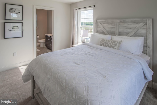 bedroom with connected bathroom and dark carpet