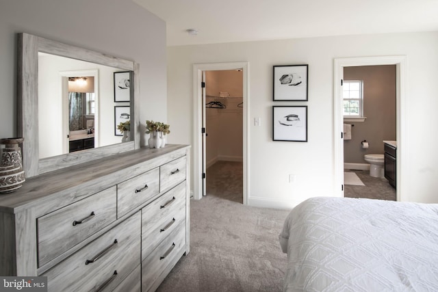 carpeted bedroom featuring a spacious closet, ensuite bath, and a closet