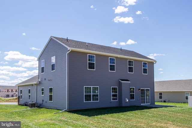 back of property with central AC unit and a lawn