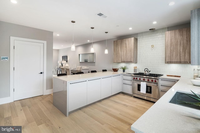 kitchen featuring pendant lighting, light hardwood / wood-style flooring, luxury stove, tasteful backsplash, and black electric stovetop