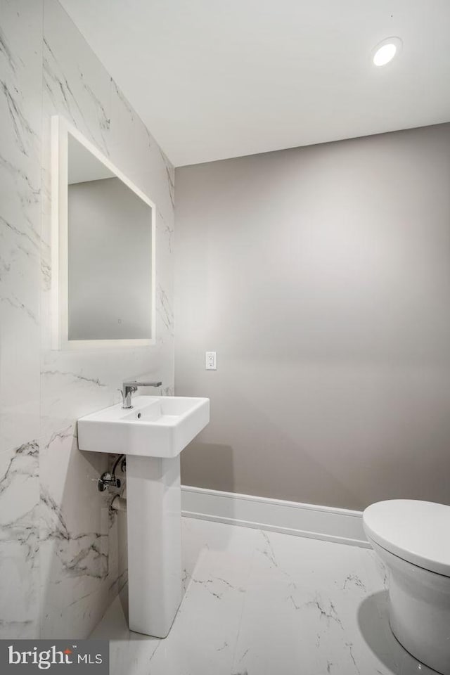 bathroom with tile flooring, toilet, and tile walls