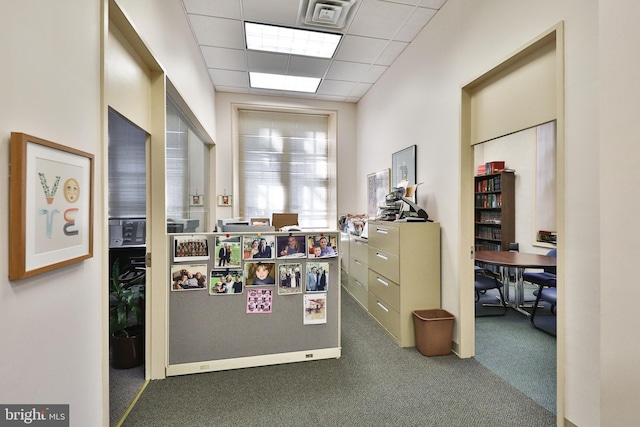 corridor featuring a paneled ceiling and dark carpet