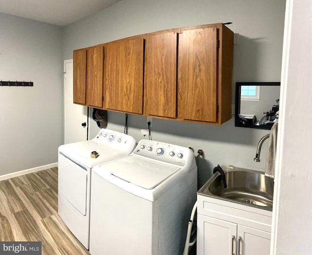 laundry area featuring cabinets, washer and dryer, sink, and light hardwood / wood-style flooring