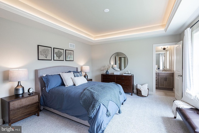 carpeted bedroom featuring a raised ceiling and ensuite bathroom