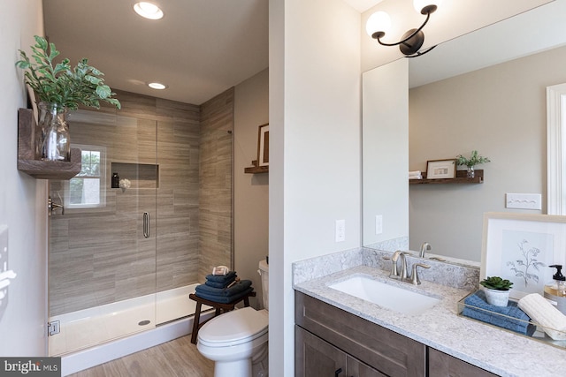 bathroom featuring an enclosed shower, vanity, hardwood / wood-style flooring, and toilet