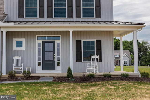 doorway to property with covered porch and a yard