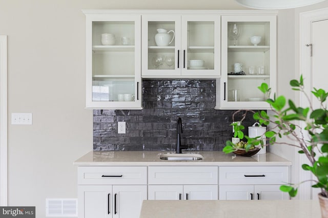 bar with sink, tasteful backsplash, and white cabinetry