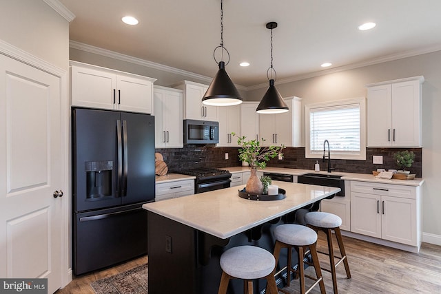 kitchen featuring pendant lighting, backsplash, a center island, and black appliances